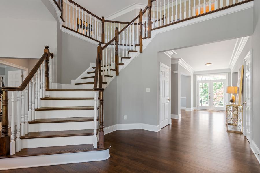Escalier en bois avec rampe et balustres blancs dans une entrée