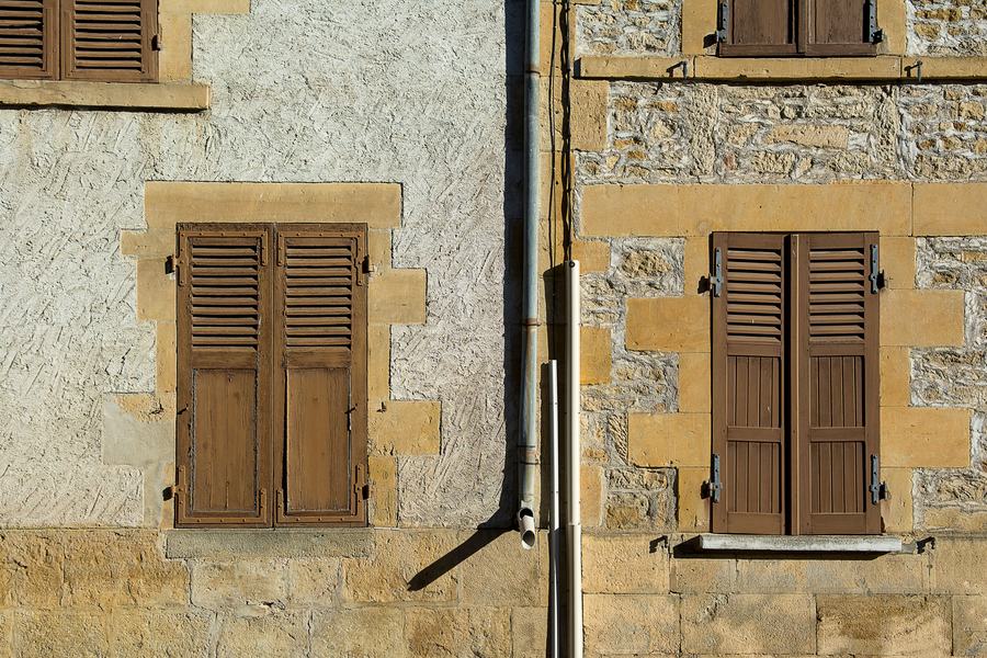 Volets en bois brun sur une façade en pierre et crépi